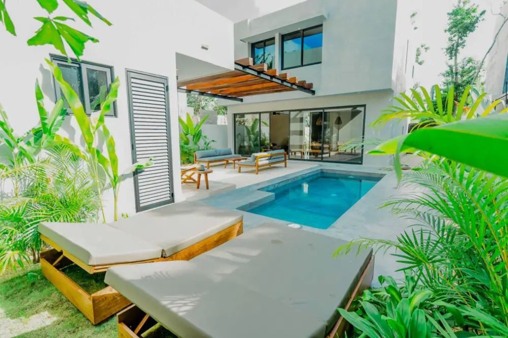 Render del patio trasero de una residencia moderna con alberca privada, camastros dobles y terrazas integradas con vegetación tropical.
