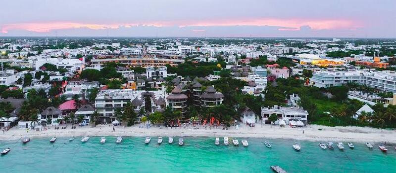 vista áerea de la costa de playa del carmen con edificios residnciales y turísticos frente al mar turquesa bajoun cielo al atardecer